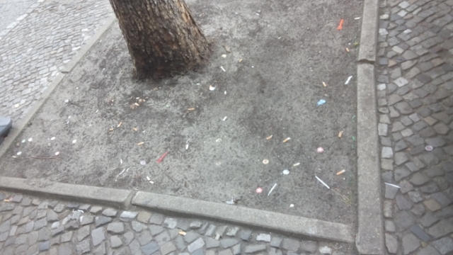 Unbepflanzte Baumscheibe voll Zigarettenkippen in Berlin