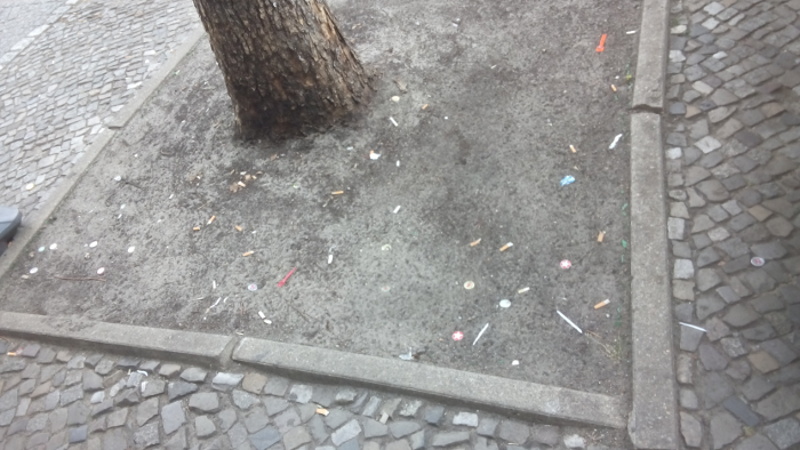 Unbepflanzte Baumscheibe voll Zigarettenkippen in Berlin
